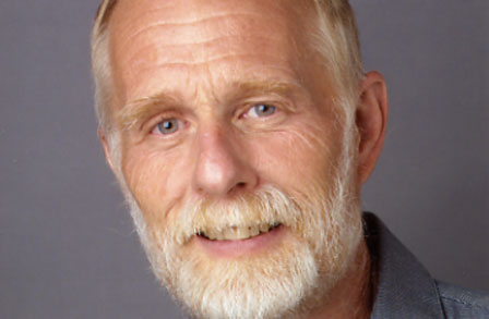 Headshot of poet Ronald Wallace in front of a grey backdrop.